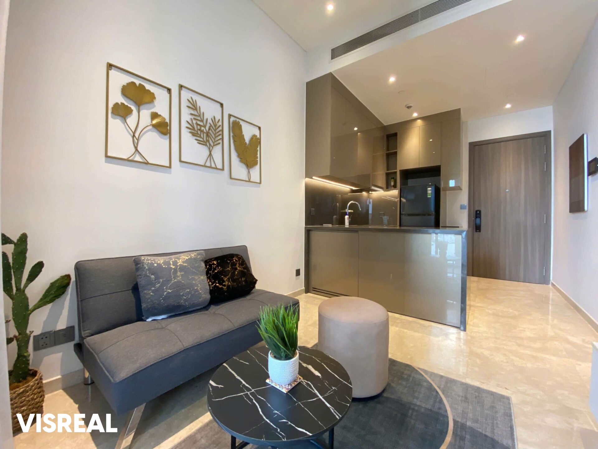 Compact living room with grey sofa and open kitchen in a 1-bedroom apartment at The Marq, District 1
