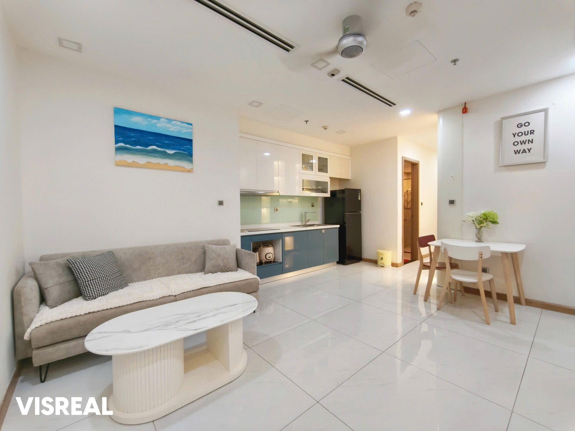 Open-plan living room with sofa, kitchen and small dining table in a 1-bedroom apartment at Vinhomes Central Park, Binh Thanh
