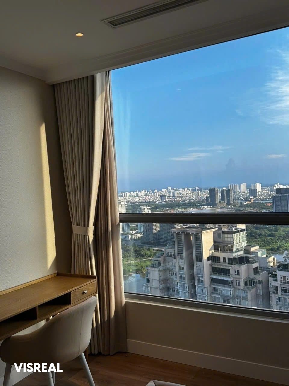Wooden work desk by a wide high-floor window in a 2-bedroom apartment at Vinhomes Central Park, Binh Thanh