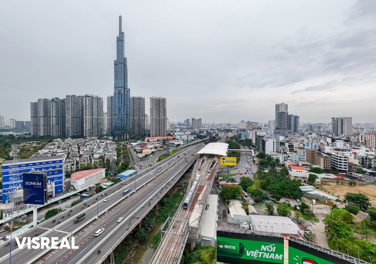 Metro Line 1 train on the raised track beside the highway, with Landmark 81 and Vinhomes Central Park towers behind